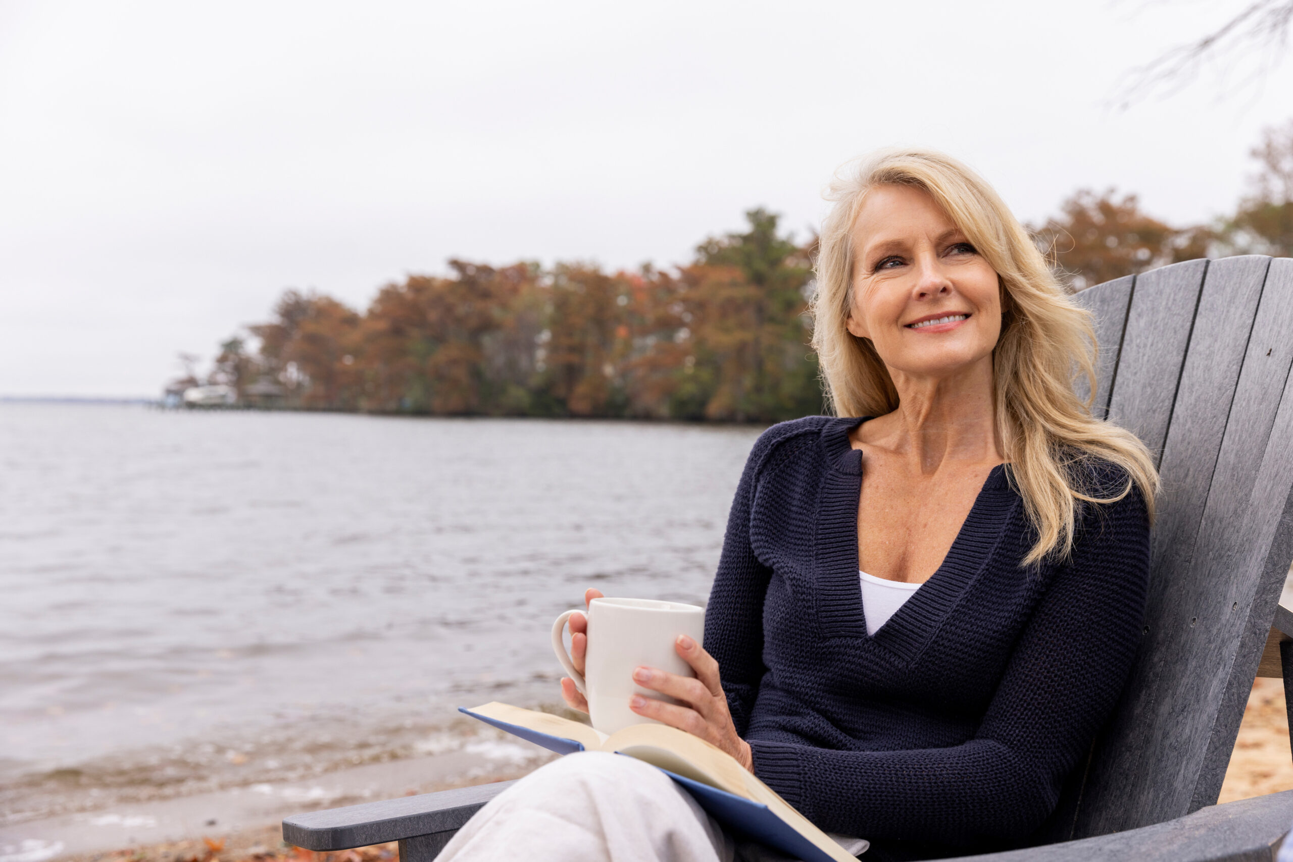 Woman relaxing with a book and coffee on the shoreline