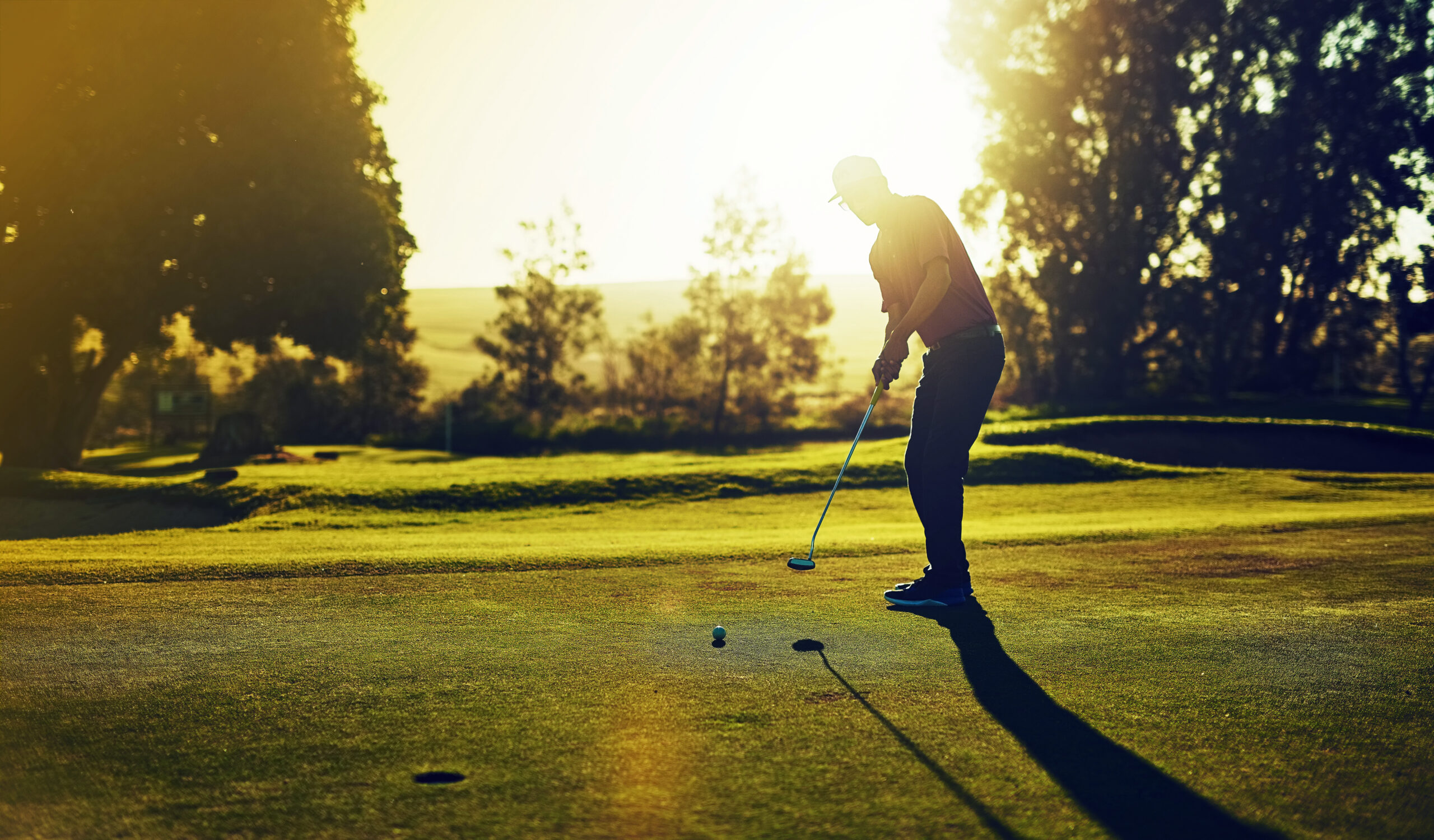 Golfer putting on the green at dusk