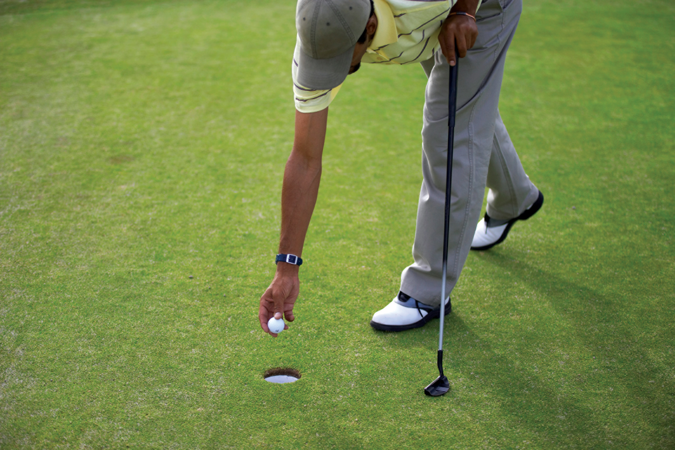 Golfer taking a golf ball out of the cup